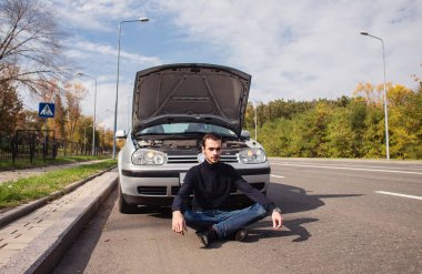 Arabasının arızası yüzünden umutsuzluğa düşmüş bir adam. 