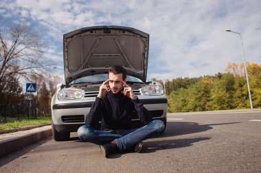 Arabasının arızası yüzünden umutsuzluğa düşmüş bir adam. 