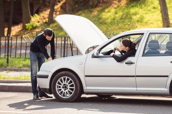 这个男人想帮助一个年轻女人修理她的车 但不知道有什么问题 — 图库照片