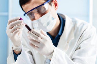 Bir virüs doktoru, Covid-19 virüslü bir kan örneğini inceliyor..