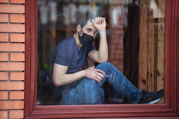 隔離中は男が家にいる コロナウイルスのパンデミック 男は窓から外を見ると — ストック写真