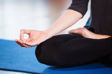 Yogacı kız evde meditasyon yapıyor ve eliyle zen sembolü yapıyor. Yogadaki kadın vücudunun yeşil bir hasırda duruşu.