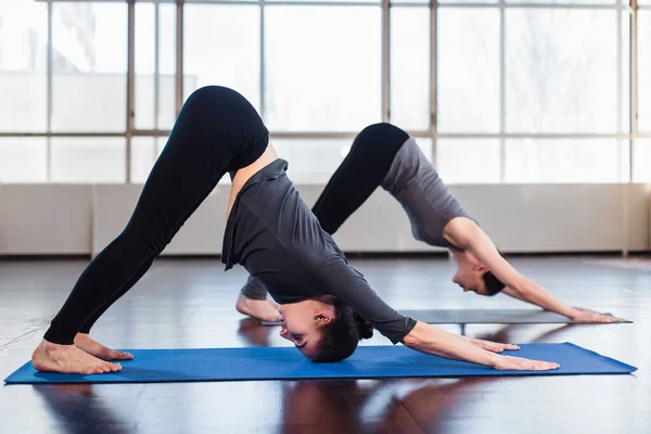 Dos Jóvenes Haciendo Yoga Sala Fitness Pose Dog Boca Abajo —  Fotos de Stock