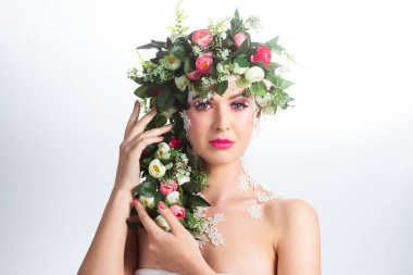 Güzel bir esmerin portresi. Kocaman kirpikleri var. Beyaz bir arkaplanda gül çelengi var..