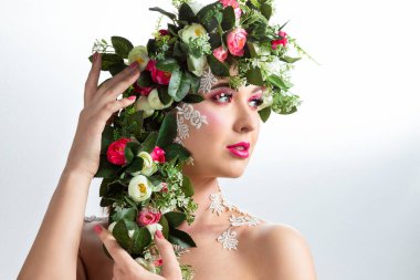 Güzel bir esmerin portresi. Kocaman kirpikleri var. Beyaz bir arkaplanda gül çelengi var..