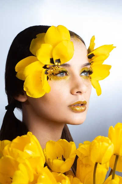 Beauty portrait of a brunette with extended eyelashes in the image of a tulip.