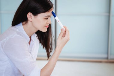 Genç bir kadın pozitif bir hamilelik testi gördüğünde şok olur ve üzülür. Testi kamerada gösterir