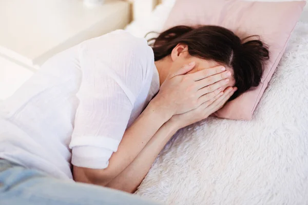 ベッドに横になって泣いている若い女性 彼女の顔を手で覆い — ストック写真