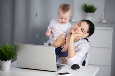 Uykulu bir anne kollarında kaprisli bir çocukla çalışmaya çalışır. Bir kadın baş ağrısı çeker.