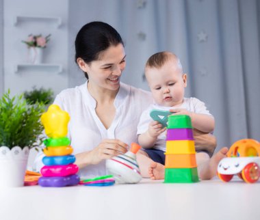 Anne ve küçük oğlu farklı oyuncaklarla oynuyor. Parlak bir çocuk odasında.