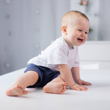 Küçük bir çocuğun portresi. Bebek parlak bir odada oturuyor..