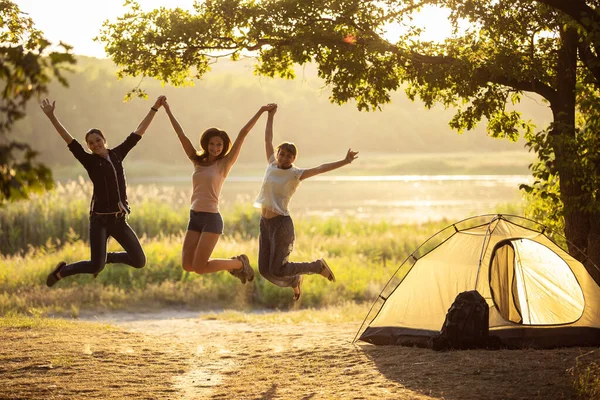 Drie Vrienden Springen Bij Zonsondergang Bij Tent Groep Toeristen Een — Stockfoto