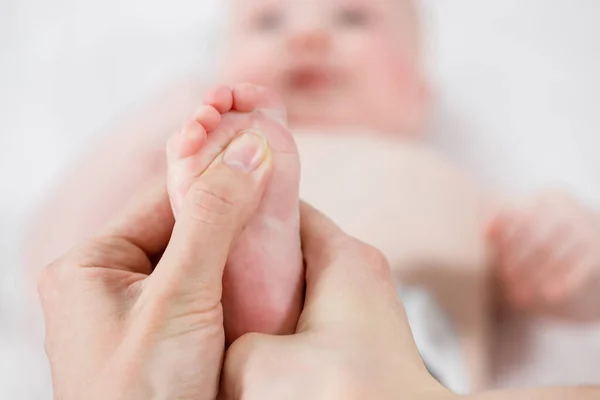 Mother does a foot massage to a newborn baby. mother\'s care. healthy lifestyle. Face is blurred in background. Close-up