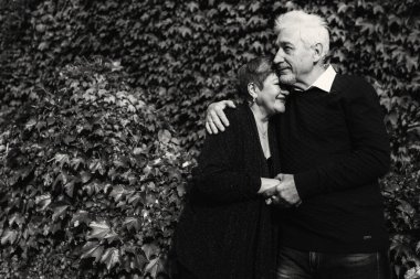 Sonbahar parkında birbirine aşık yaşlı bir çift yürüyor. Yaşlı insanlar birbirlerine sarılırlar. Siyah beyaz fotoğraf