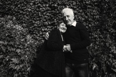 Sonbahar parkında birbirine aşık yaşlı bir çift yürüyor. Yaşlı insanlar birbirlerine sarılırlar. Siyah beyaz fotoğraf