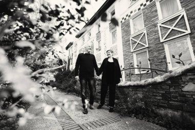 Sonbahar parkında yürüyen yaşlı bir çift. Siyah beyaz fotoğraf.