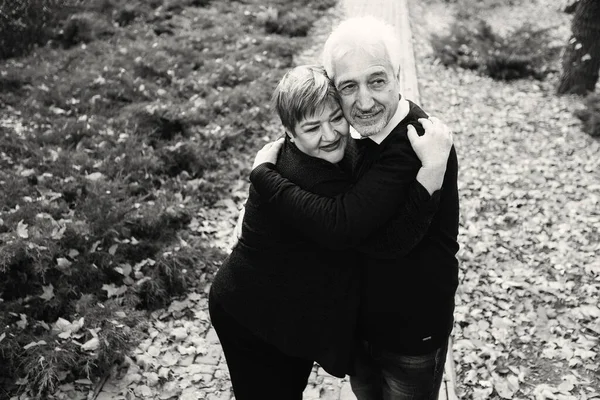 Elderly couple in love walking in the autumn park. Older people hug each other.Black and white photo