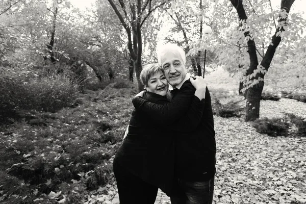 Elderly couple in love walking in the autumn park. Older people hug each other.Black and white photo