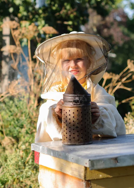 Μικρό κορίτσι μελισσοκόμος φυσάει καπνιστής για τις μέλισσες — Φωτογραφία Αρχείου