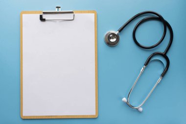 Metin için mavi arkaplan üzerinde pano bulunan steteskop.