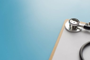 Metin için mavi arkaplan üzerinde pano bulunan steteskop.