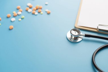 Metin için mavi arkaplan üzerinde pano bulunan steteskop.