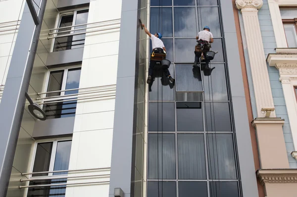 Dois trabalhadores serviço de limpeza de janelas em edifício alto Imagem De Stock