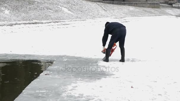Człowiek kawałki lodu z piłą na zamarzniętym jeziorze — Wideo stockowe