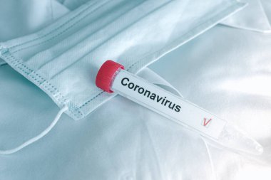 Coronavirus testi. Test tüpü ilham verici koruyucu solunum maskesinin üzerinde yatıyor. COVID-19 testi ya da SARS-CoV-2 testi. Yayılmayın.