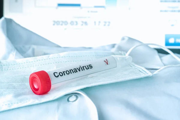 Coronavirus testi. Test tüpü ilham verici koruyucu solunum maskesinin üzerinde yatıyor. COVID-19 testi ya da SARS-CoV-2 testi. Yayılmayın.