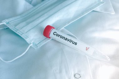 Coronavirus testi. Test tüpü ilham verici koruyucu solunum maskesinin üzerinde yatıyor. COVID-19 testi ya da SARS-CoV-2 testi. Yayılmayın.