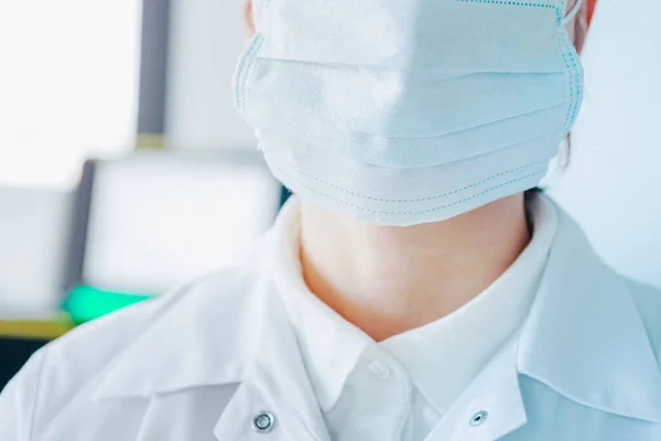 young woman in medical face protection mask indoors on laboratory background