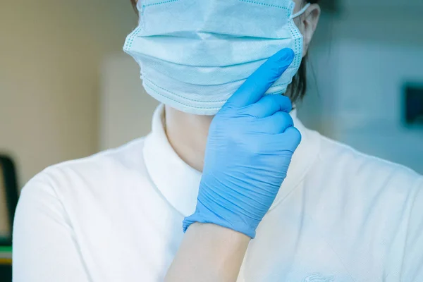 young woman in medical face protection mask and gloves indoors on laboratory background