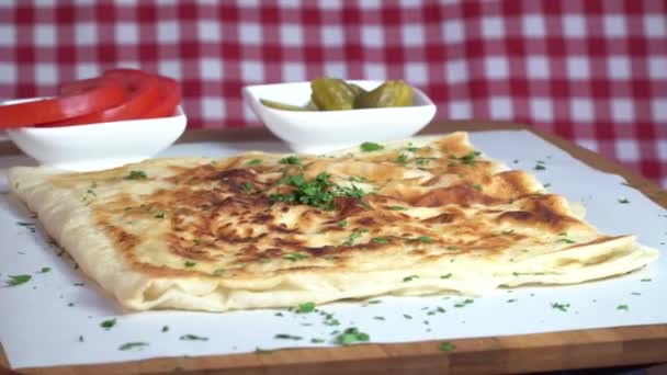 Turco tradicional Gozleme pita batatas com pepino e tomate fatiado girando em tecido padrão escocês — Vídeo de Stock