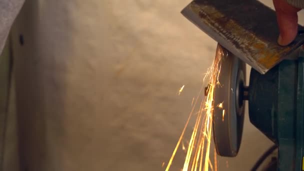 Kovové dělník v továrně broušení Železná sekera s jiskry — Stock video