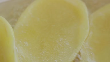 Büyük bir patates cipsi seramik tavada kızartma dilimlenmiş. Kaynayan yağ. Yakın çekim. Makro çekim.