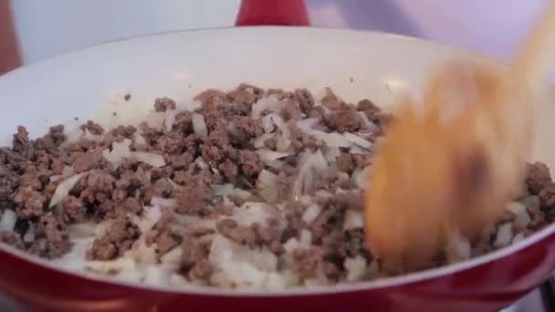 Chef mixing frying ground meat with sliced onions on ceramic pan. — Stock Video