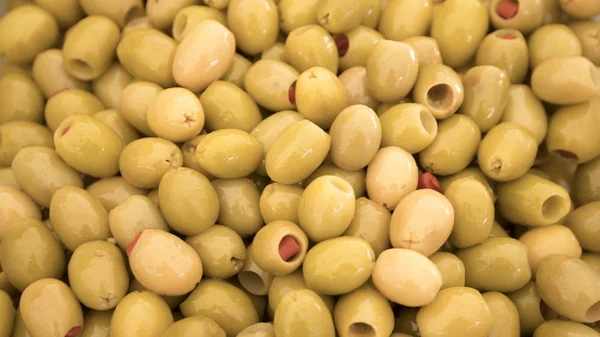 Turkiska gröna oliver med fyllda med röd paprika på stativ bazaar, bakgrund. Selektivt fokus. — Stockfoto