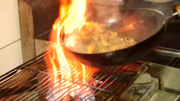 Asiatisk restaurang, kinesisk kock Matlagning med rött kött och grönsaker i woken panorera i brand. Rör fry pan med flames. Slow motion. — Stockvideo