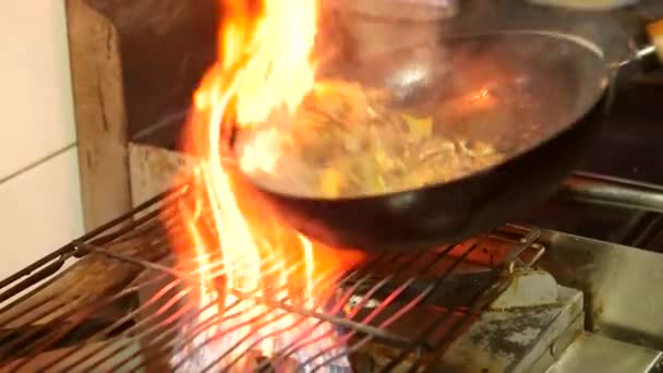 Ázsiai étterem, kínai szakács főzés az élelmiszer, a vörös hús-marha- és zöldségekkel, wok serpenyőben a tüzet. Keverjük össze a lángok serpenyőben megsütjük. Lassú mozgás.