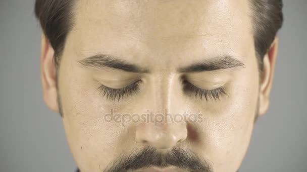 Close up van een jonge man's ogen openen. Grijze schone achtergrond — Stockvideo