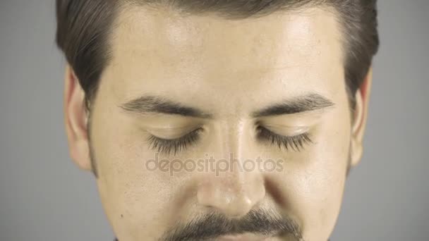 젊은 남자 오프닝 눈과 미소. 닫습니다. 어두운 회색 배경. — 비디오