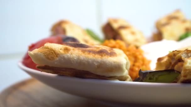 Türkisches und arabisches traditionelles Ramadan-Lammfleisch, Dönerspieß mit Zwiebeln, Bulgur, Tomaten, Petersilie, Lavasch und Salat auf rustikalem weißem Holzhintergrund. Drehschuss. — Stockvideo