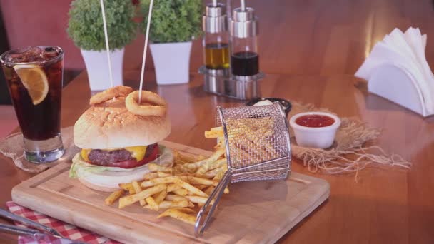 Americký cheeseburger s sýr, hovězí maso, rajče, hlávkový salát, cibule kroužky s hůlkami, hranolky a soda studený nápoj s plátkem citronu. Sklárna Nenačovice. — Stock video