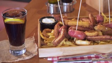 Sosis, soğan, kızarmış tavuk, schnitzel ve patates kızartması. Kızarmış fast food yemek kova ile dolu. Geleneksel bira aperatif. Yakın çekim, atış pan. 