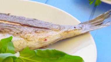 Limon, roka, dilim limon ve soğan ile plaka üzerinde ızgara çipura. Sağlıklı gıda. Mavi tablo arka planı.