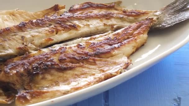 Grilled fish with onion and rocket leaves on the plate close up pan shot. Well done cook. — Stock Video