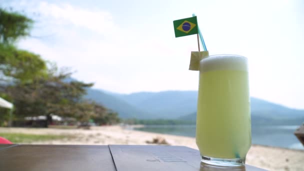 Is kallt lime saft med brasilianska flaggan på stranden — Stockvideo