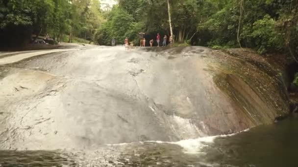 PARATY, RIO DE JANEIRO - BRASIL - AGOSTO, 2017: Gente disfrutando en una cascada. Deslizamiento sobre rocas y agua . — Vídeos de Stock