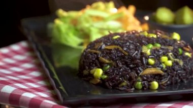 Lezzetli buharlı siyah pirinç, sağlıklı marul salatası, rendelenmiş havuç, sıcak turşu, Mısır ve yeşil bezelye fasulye siyah çanak dönen hizmet. Vegan gıda.